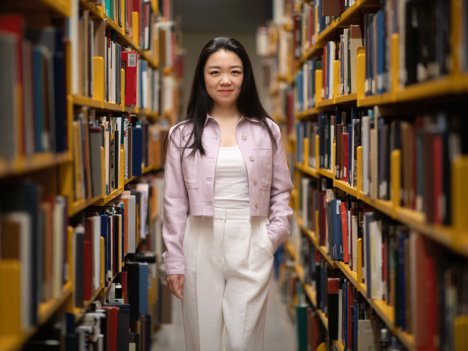 Professional photo of Yanfei Lu standing between two book shelves in a library.