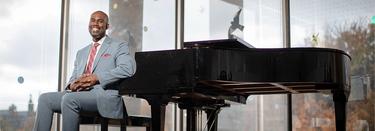 Professor Darren Hamilton sits at a piano.