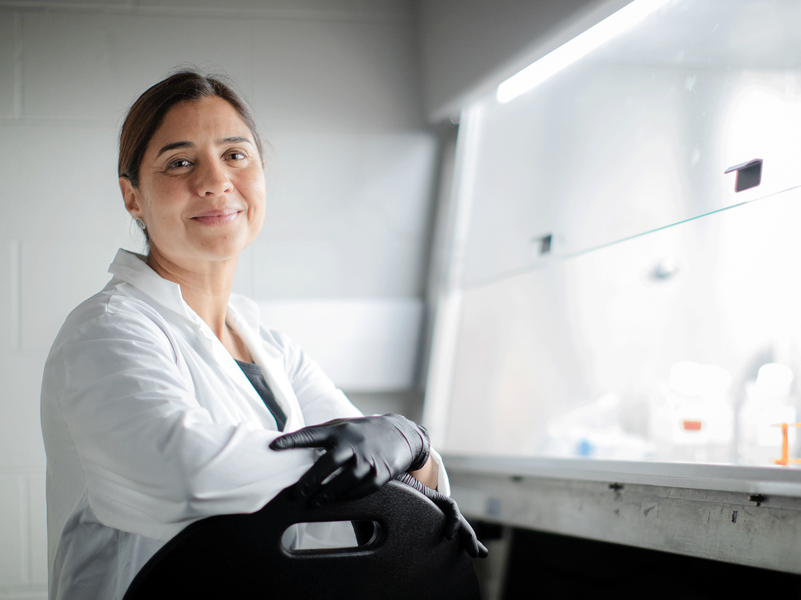 Professor Maryam Faiz working in a lab by a fume hood