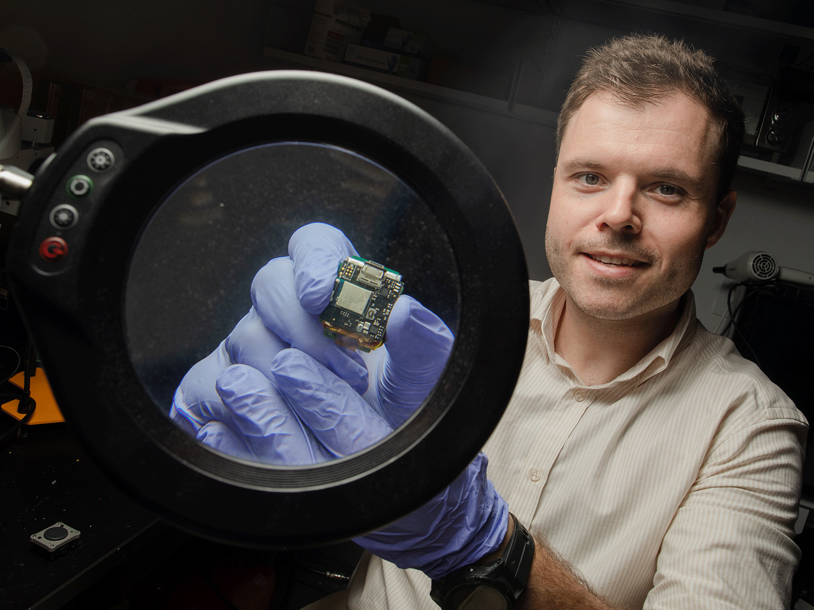 Man holds microchip up to a large magnifying glass