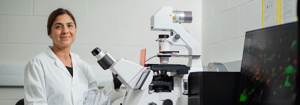 Professor Maryam Faiz using a microscope.